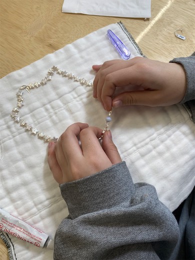 Hands working on a jewelry project on gridded paper
