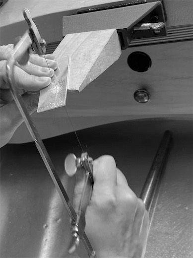 Black-and-white view of a jeweler sawing metal
